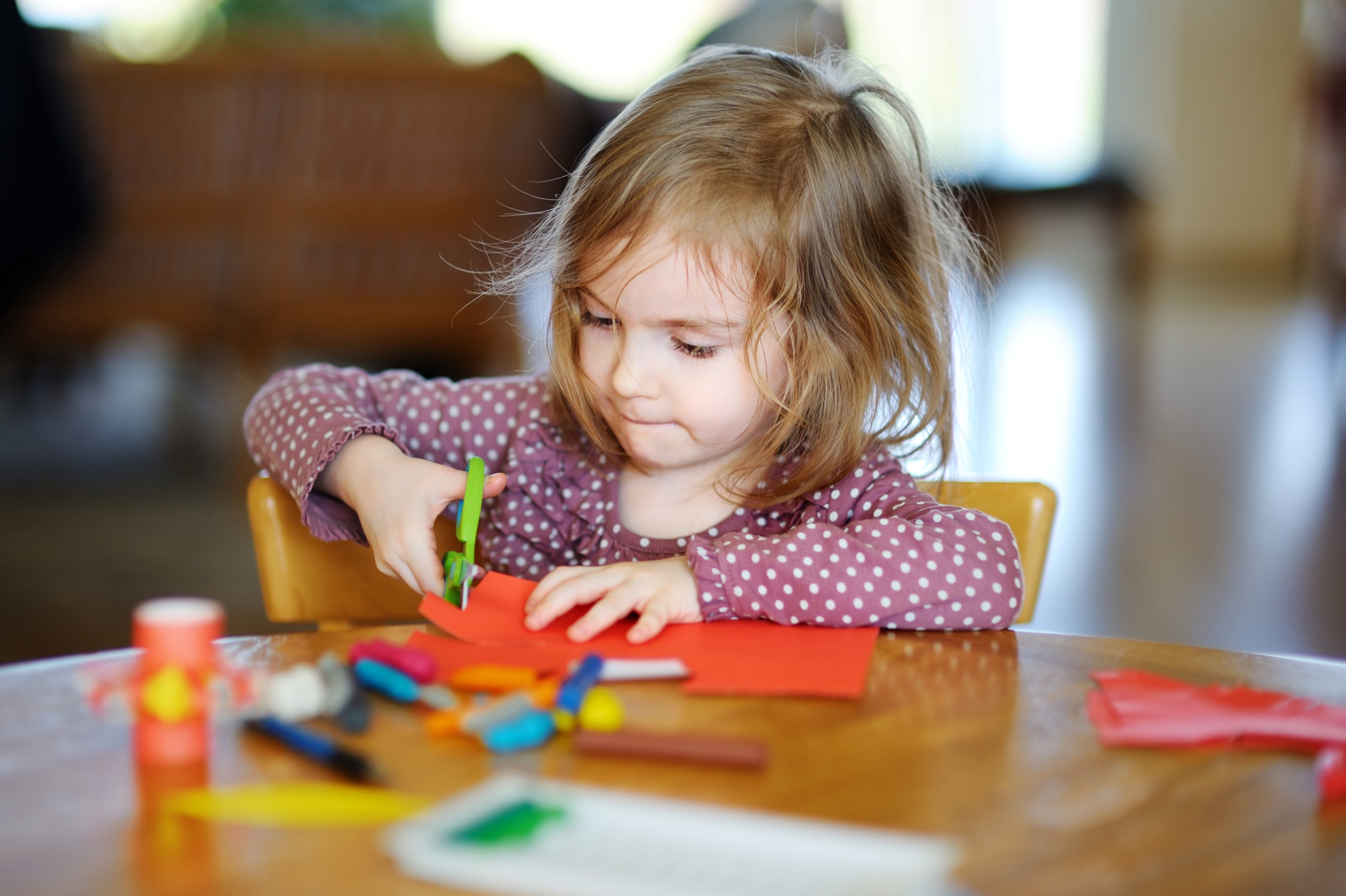 Little preschooler girl cutting paper